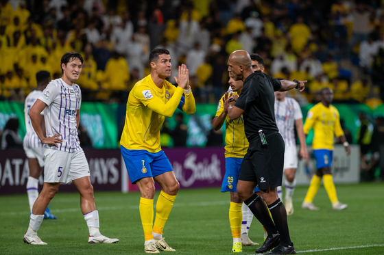 Al Nassr's Portuguese forward Cristiano Ronaldo, center, pleads with the referee while Al Ain's Korean midfielder Park Yong-woo, left, looks on during an AFC Champions League quarterfinal game at Al -Awwal Park in Riyadh, Saudi Arabia on Monday.  [ASIAN FOOTBALL CONFEDERATION]