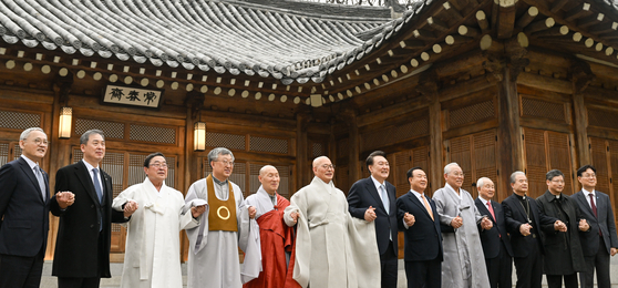 President Yoon Suk Yeol, center, takes a commemorative photo with religious leaders during a luncheon meeting held at the Blue House Sangchunjae in Seoul on Tuesday. During the meeting, he asked the religious leaders to join forces in resolving peoples' livelihood issues. [PRESIDENTIAL OFFICE]