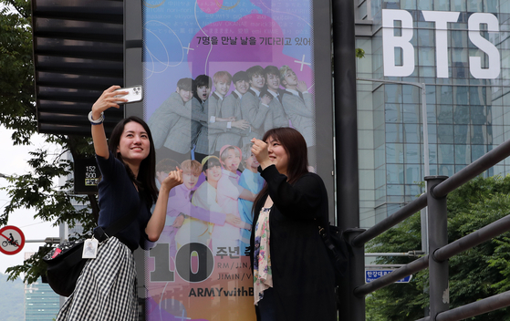 Fans of BTS pose for photos in front of the HYBE headquarters building in Yongsan District, central Seoul. [NEWS1]