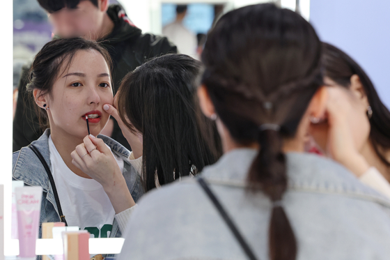 A foreign tourist tries a Korean cosmetics product in Seoul. [YONHAP]