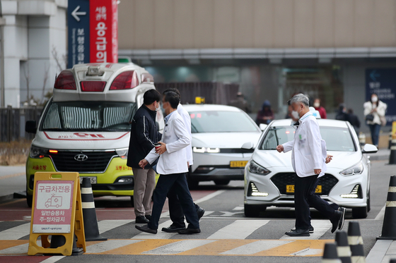 Medical professionals and doctors walk in front of a general hospital on Monday in Seoul. The government has mobilized military medical personnel for emergency medical care at regional secondary and tertiary hospitals. [NEWS1] 