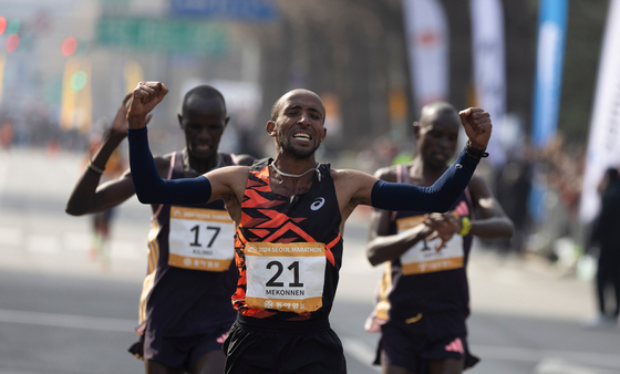Gold medalist Jemal Yimer Mekonnen of Ethiopia, center, celebrates as he crosses the finish line during the 2024 Seoul International Marathon in southern Seoul. He came in first in two hours, six minutes and nine seconds. [XINHUA/YONHAP] 