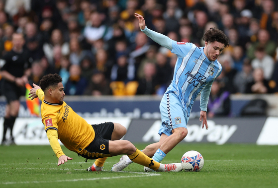 Wolverhampton Wanderers' Joao Gomes, left, in action with Coventry City's Callum O'Hare during an FA Cup quarterfinal at Molineux Stadium in Wolverhamton, England on Saturday. [REUTERS/YONHAP]