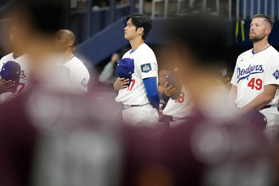 Los Angeles Dodgers' designated hitter Shohei Ohtani listens the national anthem prior to an exhibition game between the Dodgers and Kiwoom Heroes at Gocheok Sky Dome in western Seoul on Sunday.  [AP/YONHAP]