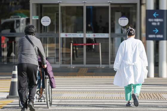 A medical professional and a patient with a guardian pass a crosswalk in front of a general hospital in Seoul on Monday. [NEWS1] 