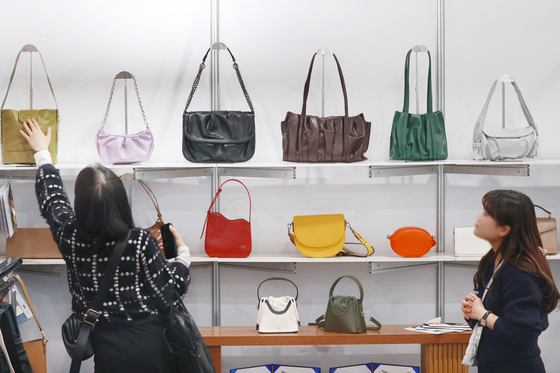 Visitors look at handbags displayed on shelves installed at "2024 SEOUL TEX & TECH" hosted at the aT Center in Seocho District, southern Seoul, on Monday. The event showcasing items combining digital technologies and fandom branding runs through Wednesday. [YONHAP]