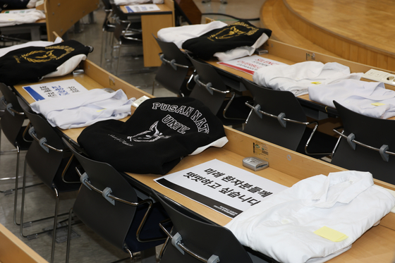 Collegiate jumpers and white gowns are placed on desks at a lecture hall at a medical college of Pusan National University on Tuesday. [YONHAP] 
