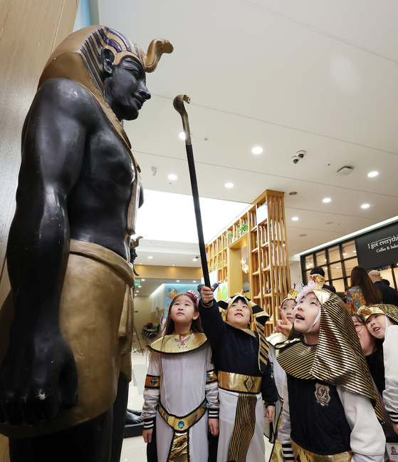Children dressed in traditional Egyptian attire look at a statue during the Egyptian culture day event held at Songpa Geulmaru Library, a public library in Songpa District, southern Seoul, on Wednesday. [YONHAP]