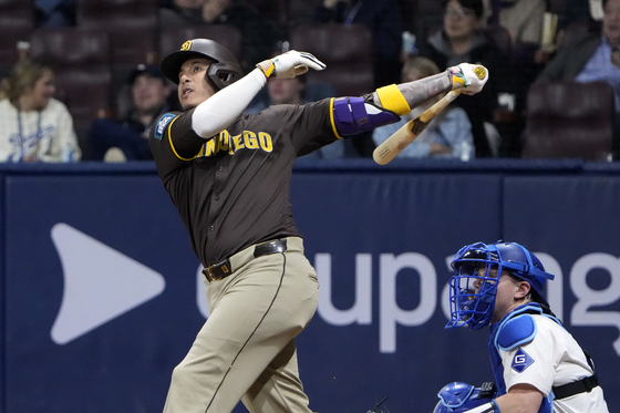 San Diego Padres' Manny Machado, left, hits a three-run home run as Los Angeles Dodgers catcher Will Smith watches during Game 2 of the Seoul Series between the San Diego Padres and Los Angeles Dodgers at Gocheok Sky Dome in western Seoul on Thursday.  [AP/YONHAP]