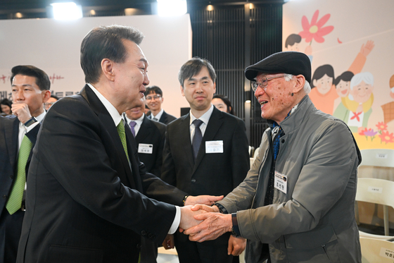 President Yoon Suk Yeol, left, shakes hands with an elderly during a public livelihood debate held at the headquarters of the Health Insurance Review & Assessment Service in Wonju, Gangwon, Thursday. [PRESIDENTIAL OFFICE] 