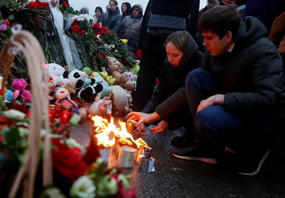 People light candles on Saturday at a makeshift memorial to the victims of a shooting attack at the Crocus City Hall concert venue in Moscow, Russia, the previous day. [REUTERS/YONHAP]