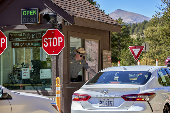 A park ranger greets visitors by collecting entrance fees at the Fall River entrance to Rocky Mountain National Park in Colo., on Sept. 21, 2023. The National Park Service is continuing to convert dozens of its sites across the country to cashless payments only, drawing complaints and, now, a lawsuit. [Stephen Speranza /The New York Times]