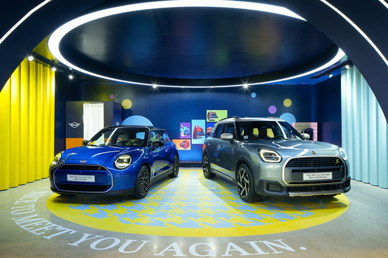 The new all-electric Mini Cooper, left, and Mini Countryman models on display at an exhibition titled "Mini Heritage & Beyond" in southern Seoul on Monday. [BMW KOREA]