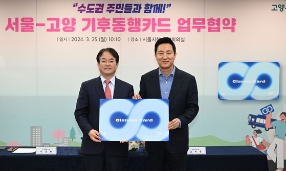 Goyang Mayor Lee Dong-hwan, left, poses for a photo with Seoul Mayor Oh Se-hoon after signing an agreement to join the capital's unlimited transit pass Climate Card scheme at City Hall in downtown Seoul on Monday. [JOINT PRESS CORPS]