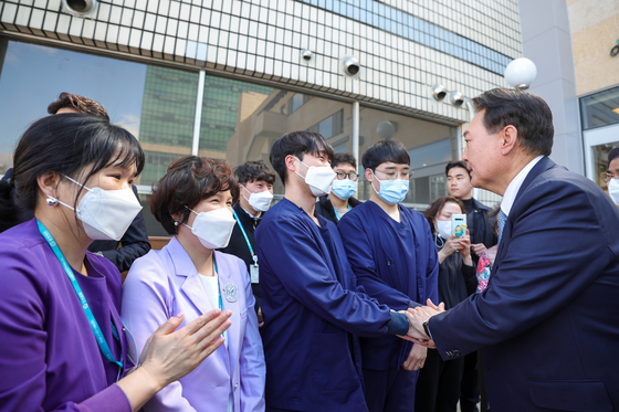 President Yoon Suk Yeol, right, shakes hands with medical professionals at Hankook General Hospital in North Chungcheong on Tuesday. [PRESIDENTIAL OFFICE]