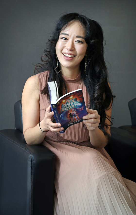 Author Graci Kim with a copy of ″The Last Fallen Star,″ the first installment of the ″Gifted Clans″ trilogy, during an interview with the Korea JoongAng Daily at the New Zealand Embassy in Jung District, central Seoul, on March 22, 2024. [PARK SANG-MOON]