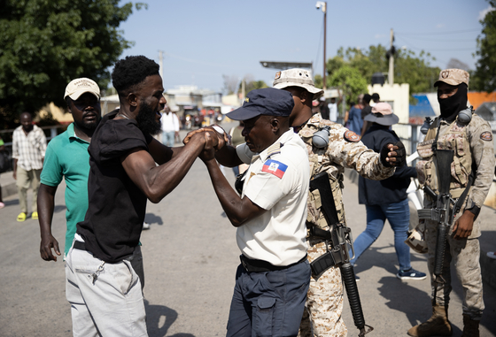 A Haitian police officer tries to subdue a man who had crossed without authorization into the Binational Market and who was expelled by the Dominican military to his country, in the border area of Dajabon, Dominican Republic, on Sunday. [EPA/YONHAP]