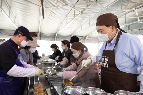 President Yoon Suk Yeol, right, serves meals to visitors at a soup kitchen in Myeong-dong, central Seoul, on Wednesday. [PRESIDENTIAL OFFICE] 