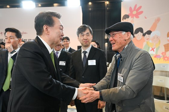 President Yoon Suk Yeol, left, shakes hands with an older adult during a public livelihood debate held at the headquarters of the Health Insurance Review & Assessment Service in Wonju, Gangwon, on Thursday. [PRESIDENTIAL OFFICE]