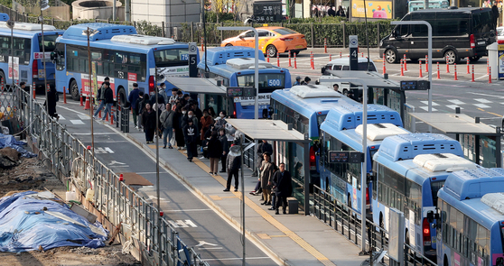 Commuters wait for buses at Seoul Station Bus Transfer Center in downtown Seoul on Wednesday. Unionized intracity bus drivers and representatives of management had last-minute negotiations on the same day over wage hikes, a day before the union's planned general strike. The unionized workers were set to go on strike from 4 a.m. Thursday if an agreement was not reached by midnight Wednesday. [YONHAP] 