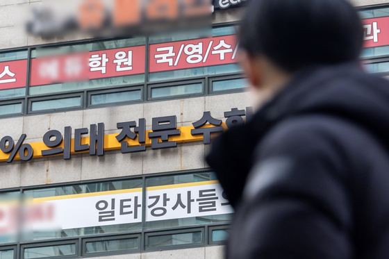 A person looks at the banners of private cram schools in Mok-dong of Yangcheon District, western Seoul, recruiting students interested in applying to medical schools, on Feb. 8. [YONHAP]