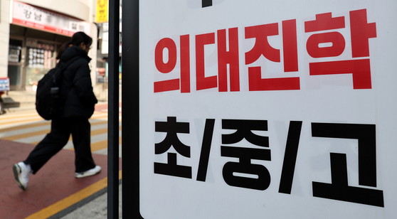 A person on Tuesday walks past an advertisement for a private cram school in southern Seoul recruiting students from elementary to high school to attend classes for medical school admission. [NEWS1]