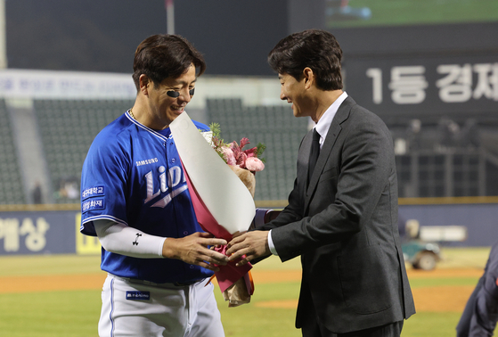 Former KBO hitter and sports commentator Park Yong-taik congratulates Samsung Lions' Kang Min-ho for breaking his record for the most games played in the KBO at Jamsil Baseball Stadium in southern Seoul on Thursday. [YONHAP]