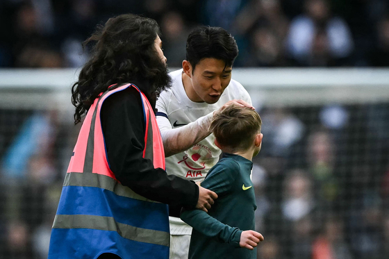 Tottenham Hotspur's Son Heung-min greets a young pitch invader and the end of a Premier League match against Luton Town at Tottenham Hotspur Stadium in London on Saturday.  [AFP/YONHAP]