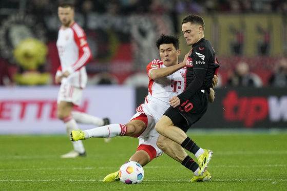 Bayern's Kim Min-jae, left, and Leverkusen's Florian Wirtz challenge for the ball during a match at the BayArena in Leverkusen, Germany, on Feb. 10. [AP/YONHAP]