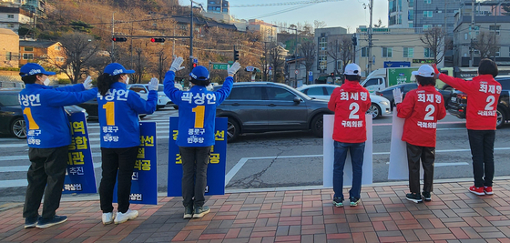 Supporters of Democratic Party candidate Kwak Sang-eon, left, and People Power Party candidate Choi Jae-young campaign side by side along a road in Jongno District, central Seoul, on Monday, nine days before the general election. [YONHAP]