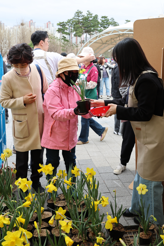 Pedestrians exchange recyclable trash for a flower pot at a park in Amsa-dong, Gangdong District in eastern Seoul on Wednesday. The campaign, hosted by the Seoul Metropolitan Government, aims to promote recycling. [YONHAP]