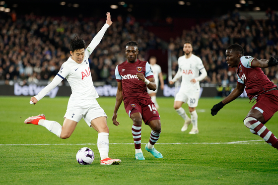 Tottenham Hotspur's Son Heung-min, left, takes a shot on goal under pressure from West Ham's Mohammed Kudus at London Stadium in London, England on Tuesday. [YONHAP]