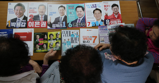 Elderly voters look at campaign leaflets from candidates for the April 10 general election in Daejeon on Wednesday. [NEWS1]