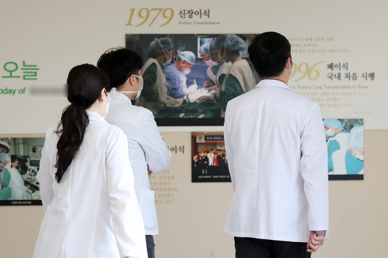 Three medical professionals stand inside a general hospital in Seoul on Friday. [NEWS1]