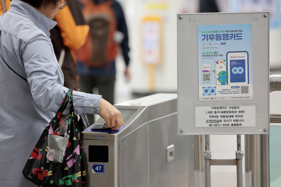 A person passes through the subway turnstiles at the platform at Gwanghwamun Station in central Seoul on Sunday, with a banner advertising the Climate Card unlimited public transportation pass displayed nearby. [YONHAP]