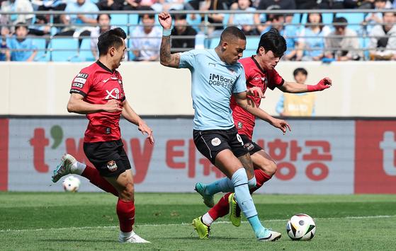 Daegu FC's Lucas Barcellos, center, rushes for the ball during a match against FC Seoul at Daegu Bank Park in Daegu on Sunday. [YONHAP]