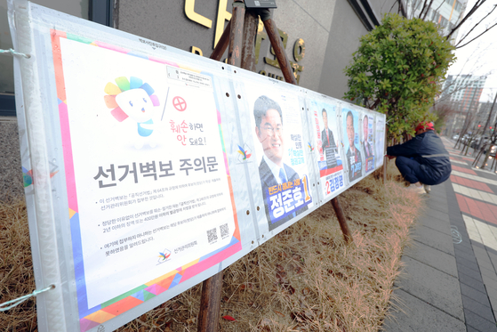 A person hangs campaign posters on March 28 in Buk District, Gwangju. [YONHAP]