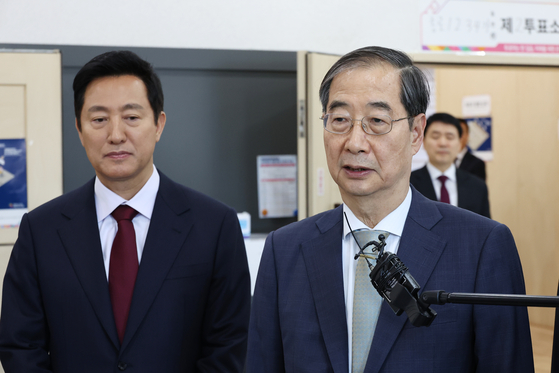 Prime Minister Han Duck-soo, right, and Seoul Mayor Oh Se-hoon visit a polling station in Jongno District, central Seoul, on Tuesday to ensure safe voting takes place the next day. [YONHAP] 