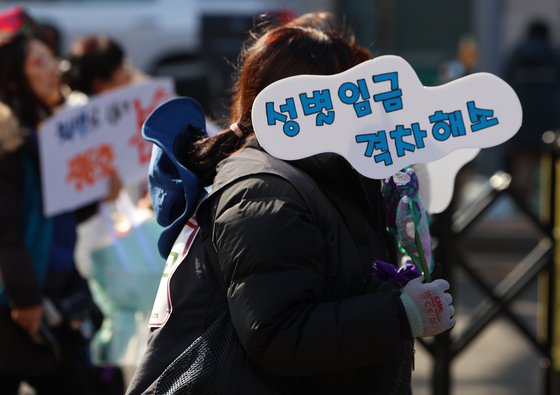 A woman marches in central Seoul with a picket demanding a reduction in the gender wage gap. [YONHAP]