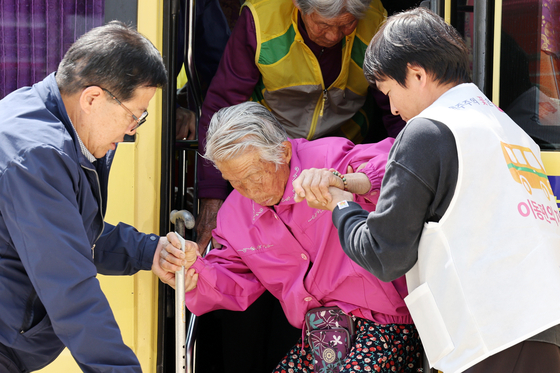 An elderly citizen gets assistance departing a bus on her way to vote at a polling station in Gokseong-gun, North Jeolla, on Wednesday. [YONHAP] 