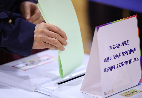 A voter submits her ballot into a ballot box at a polling station in Yeouido, western Seoul, on Wednesday [YONHAP]