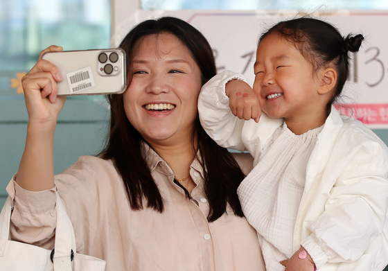 A mother and her daughter take a celebratory photo after voting at a polling station in Daegu on Wednesday. [NEWS1]
