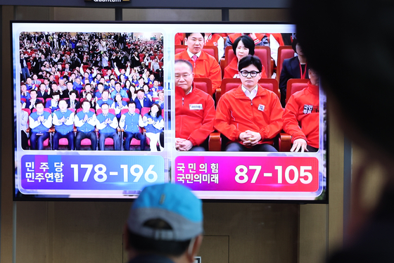 People watch a live broadcast of general election outcome predictions based on the joint exit poll conducted by KBS, MBC and SBS on a television screen inside Yongsan Station in central Seoul on Wednesday evening. [NEWS1]