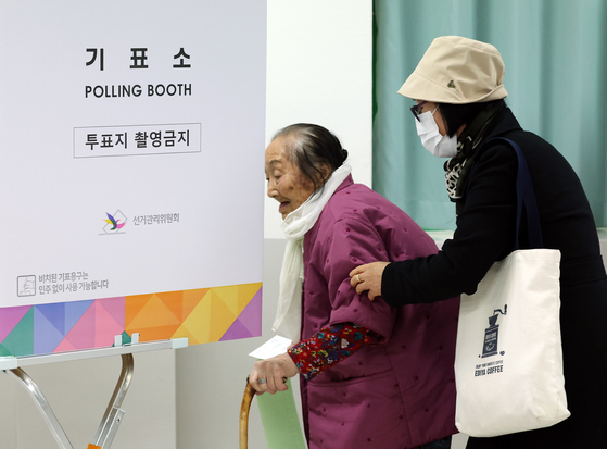 A 100-year-old woman casts her ballot for the general election at a middle school in Ulsan on Wednesday. [YONHAP]