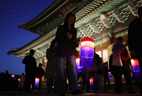 Participants at Changdeok Palace's ″A Nocturnal Walk under the Moon″ last year enjoy a walk inside the palace with a traditional lantern. [YONHAP] 