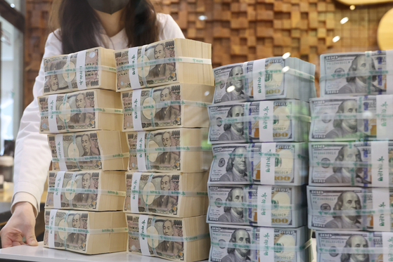 An employee stands behind organized stacks of dollar and yen bills at Hana Bank’s Counterfeit Notes Response Center in Jung District, central Seoul, on Thursday. [YONHAP]