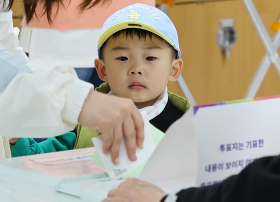 A future voter watches his mother cast her ballot at a polling station at a middle school in Michuhol District in Incheon Wednesday. [YONHAP]