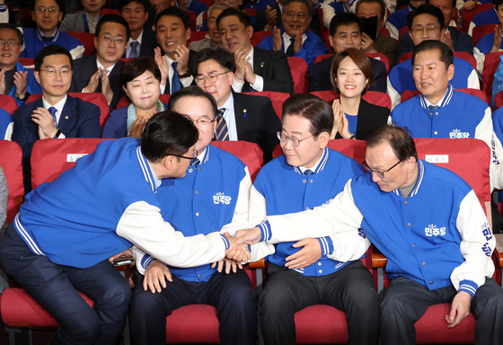 Democratic Party Chairman Lee Jae-myung, second from right, is cheerful after seeing exit poll results in favor of his party at the DP’s situation room in the National Assembly in Yeouido, western Seoul, Wednesday. [JOINT PRESS CORPS]