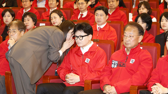 People Power Party interim leader Han Dong-hoon listens solemnly to a report from a party official after seeing the exit poll results for the general election at a PPP situation room in the National Assembly in Yeouido, western Seoul, Wednesday. [NEWS1]