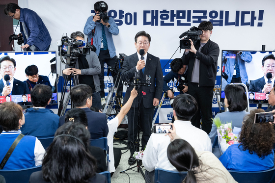 Democratic Party Chairman Lee Jae-myung, center, speaks to his supporters at his campaign office in Incheon, early Thursday, as he was projected to be re-elected in Incheon's Gyeyang-B District. [JOINT PRESS CORPS] 